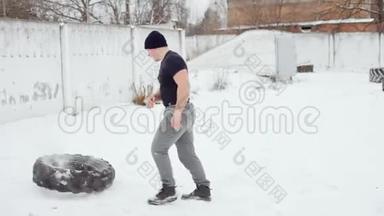 肌肉男把橡胶轮胎扔在自己身上，在冬天做交叉健身运动